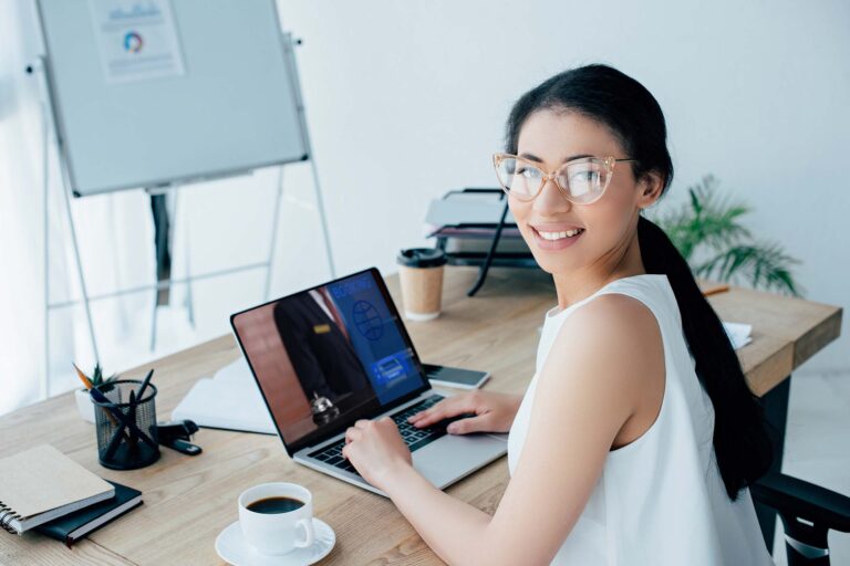 cheerful latin businesswoman using laptop with boo FA82N8N 1